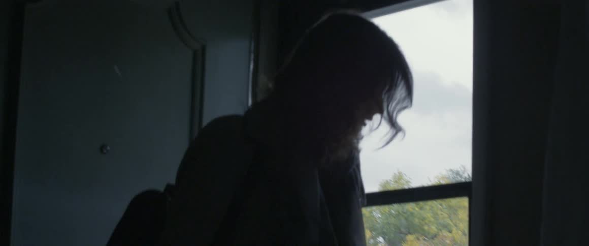A woman pulls a suitcase out the front door of a house