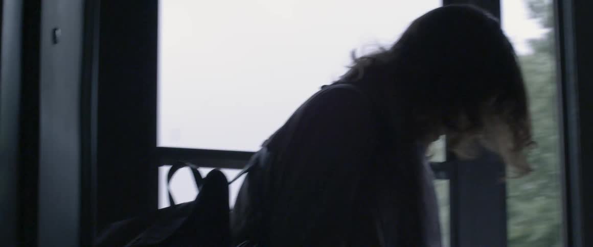 A woman exits a house pulling luggage