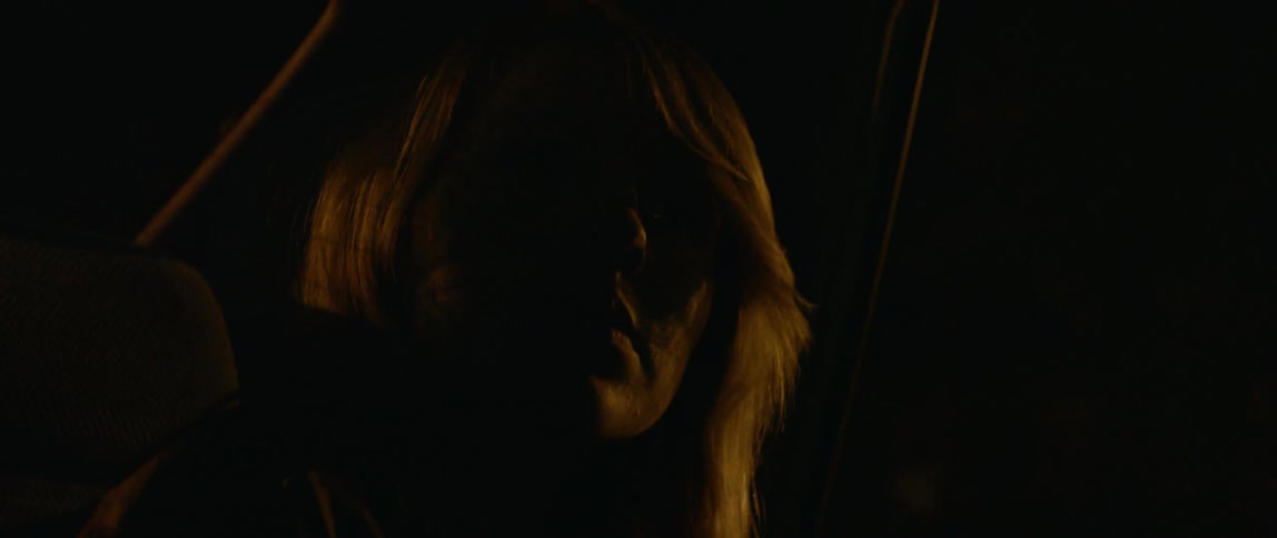 A woman rides in the back of a car at night