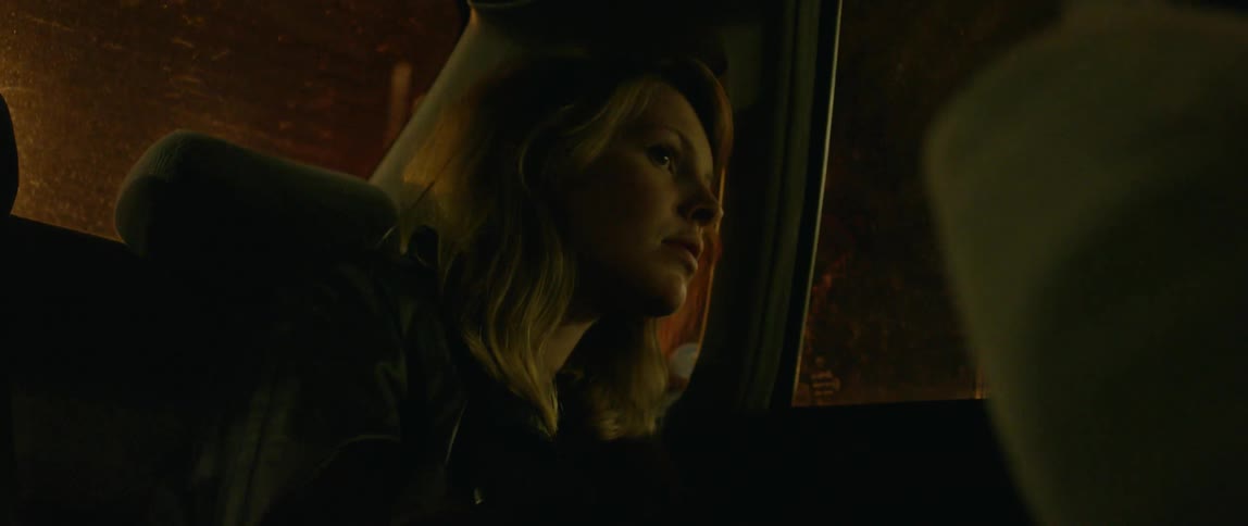 A woman rides in the back of a car at night