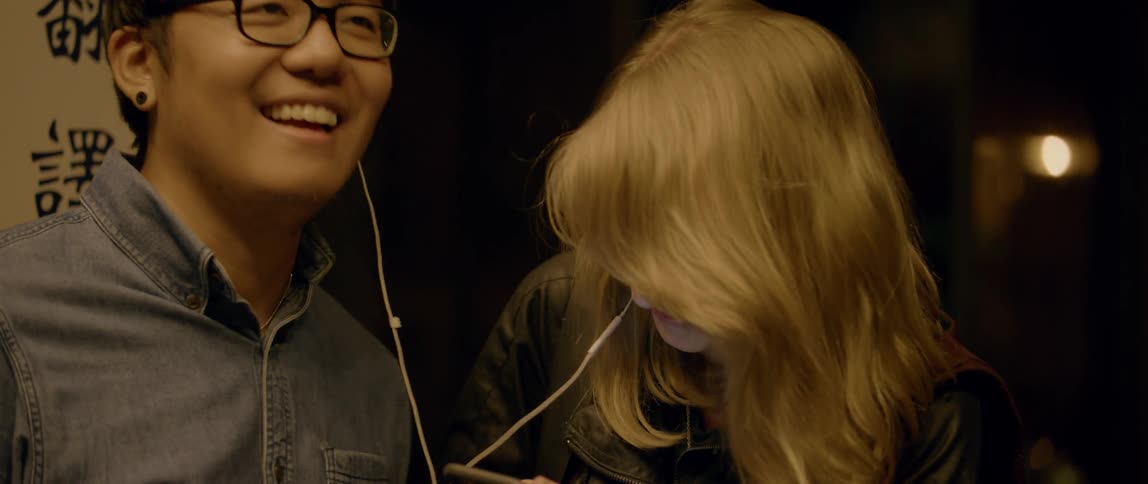 A man and woman are sharing headphones and listening to music