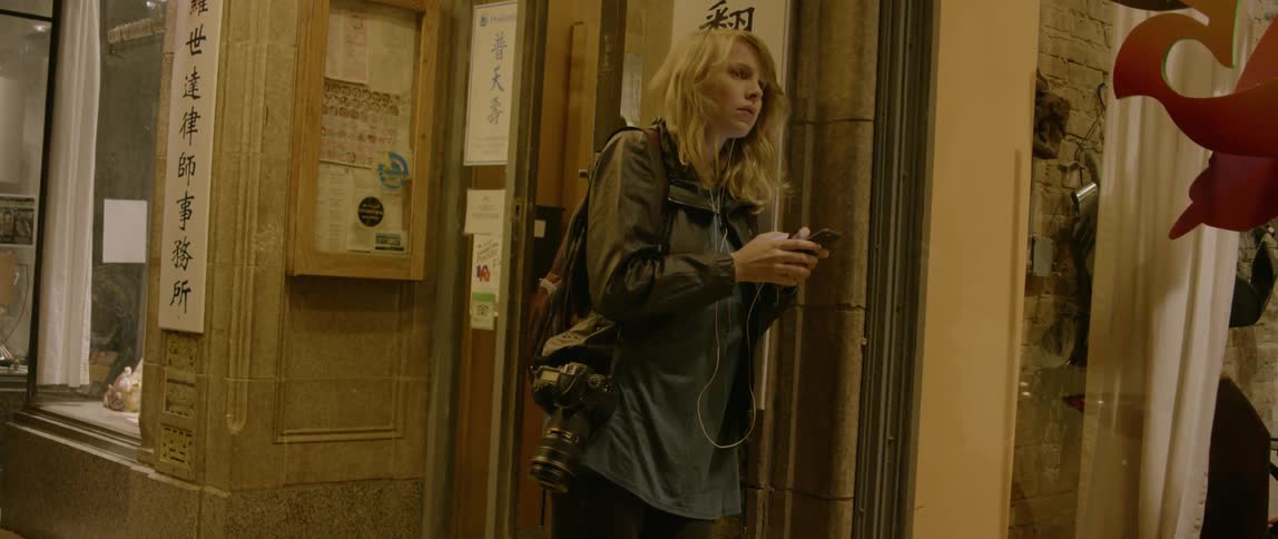Woman types on her phone in a city