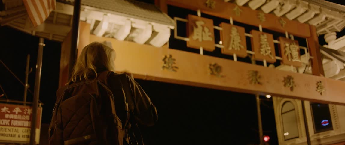 A woman stands next to a building with chinese characters