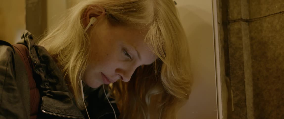 Woman listens to headphones while looking at phone