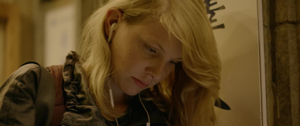A woman listens to headphones while playing on her phone