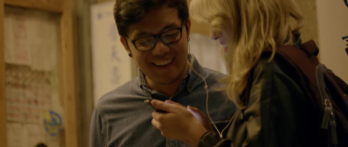 Man and woman share earbuds and smile