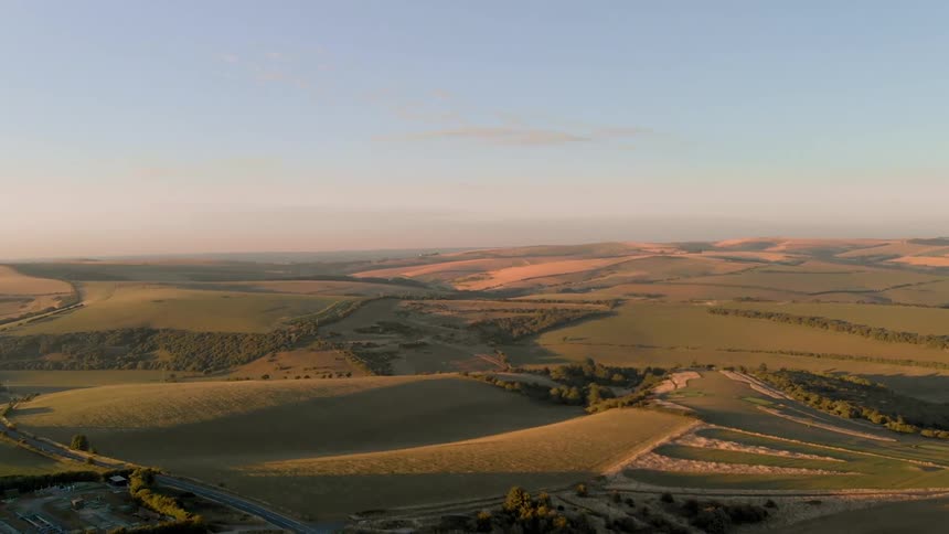 The sun is setting on the green pastures below