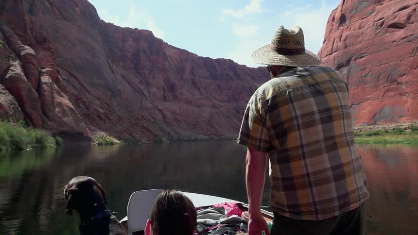 A family is taking a boat down a river between a canyon