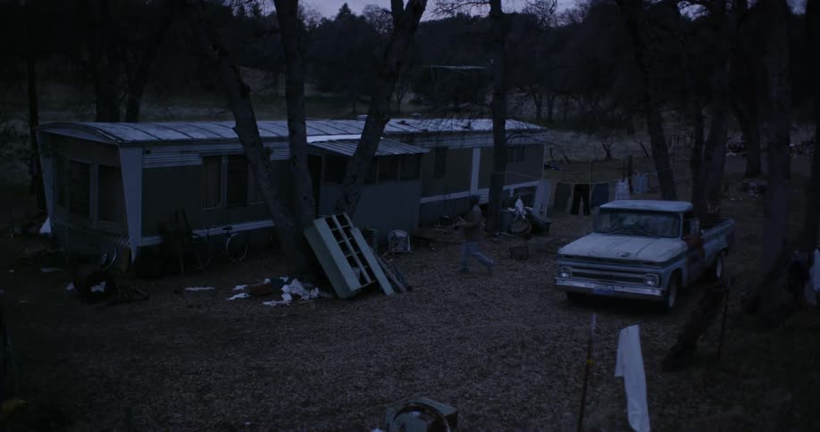 A man exits a pickup truck outside of a trailer