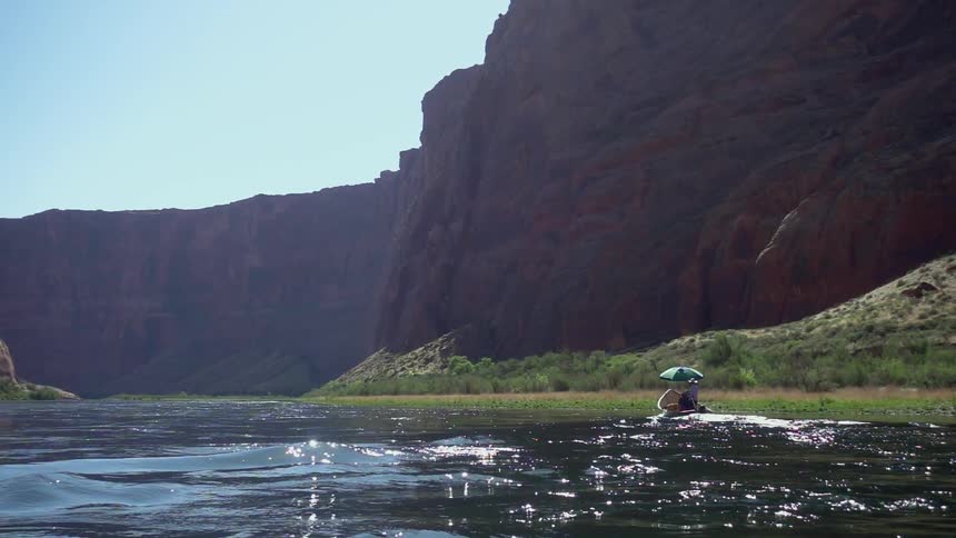 A person is sitting on the river in a canyon