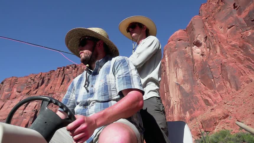 Two men in straw hats sit in a small vehicle