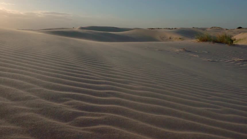 Sand dunes are shown as the sun is setting