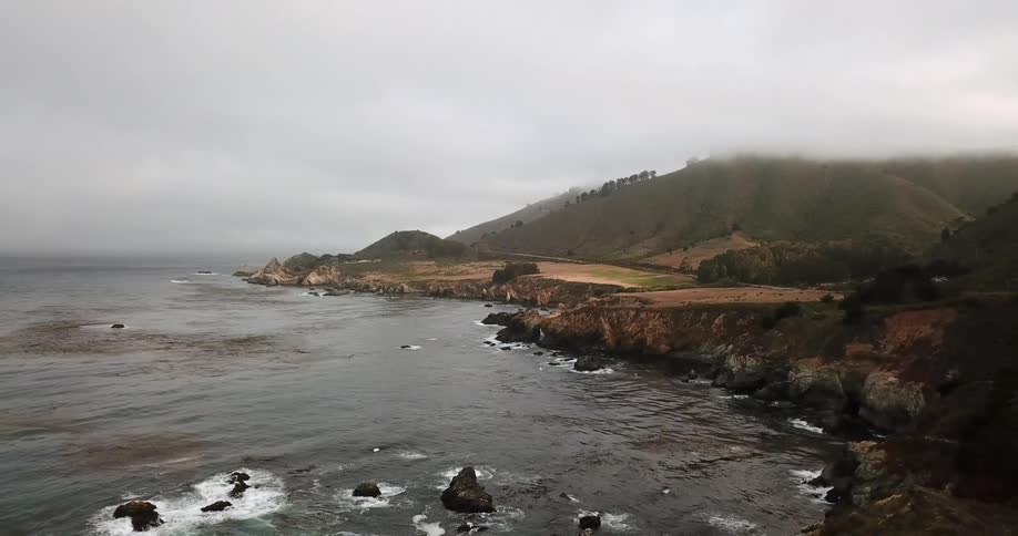 A large landmass is bordering the ocean as waves crash on the shore