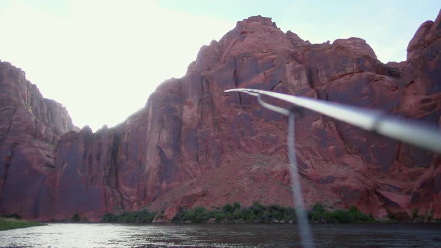 Someone is fishing in a river running by a canyon wall
