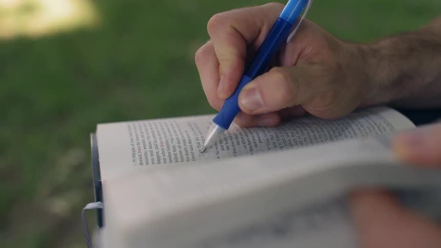 Someone is holding a pen and a book are are circling important parks of the book