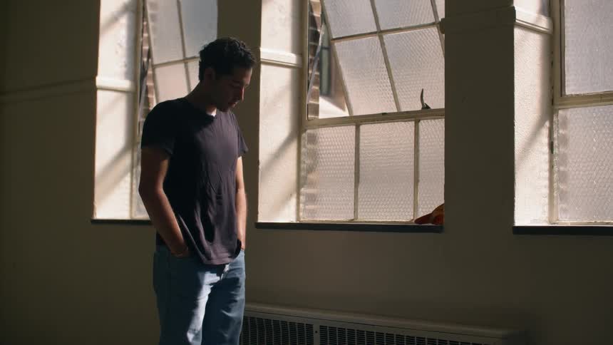 A man stands with his hands in his pockets and head bowed