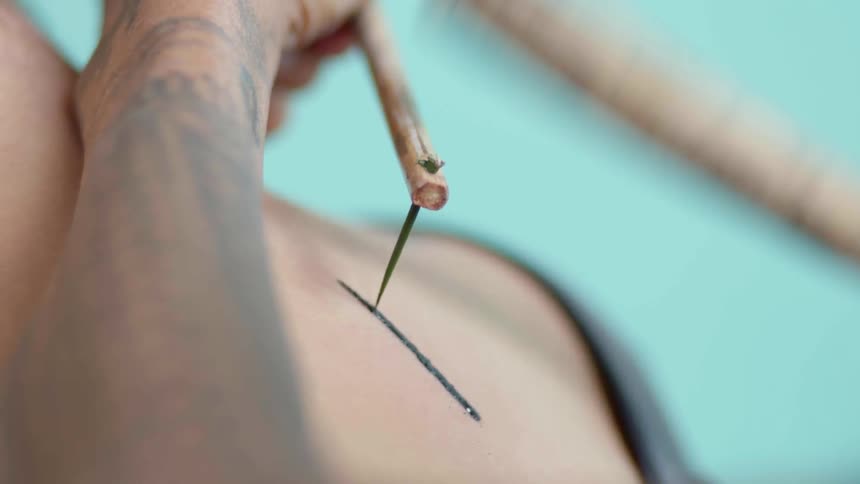 Man hammering tattoo with needle with ink on their stomach 