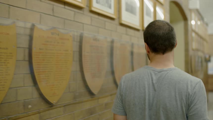 A man walks past plaques behind glass