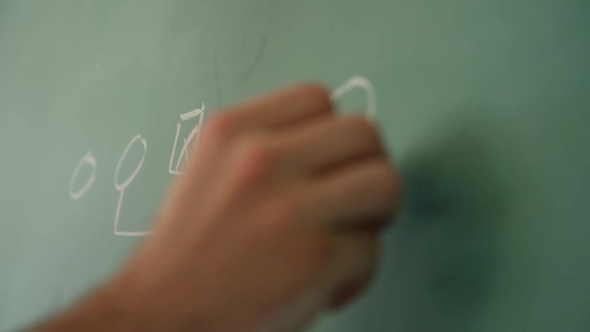 A person writes on a classroom chalkboard