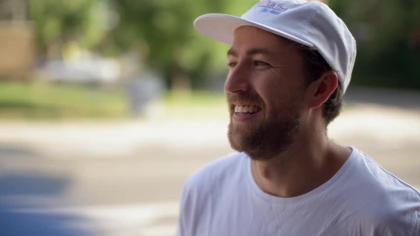 A man in a white hat is laughing while he talks to someone