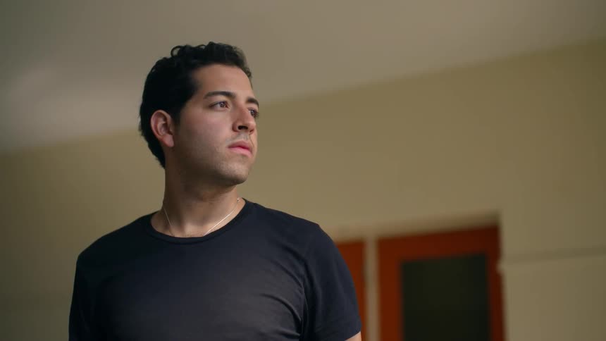 A man wearing a black shirt is standing in the room
