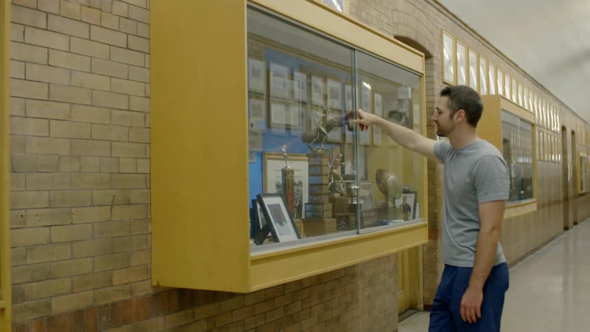 A man looks at a trophy case in a school