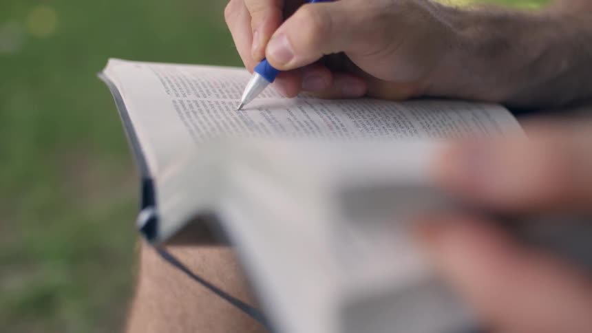 A person is writing in their book with a pen