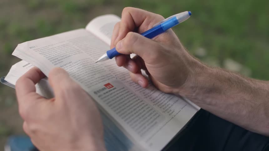 Person underlines words in a book with a pen