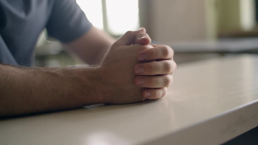 Someone is sitting at a table rubbing their hands together