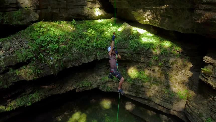 A cave diver ascends up a hanging rope
