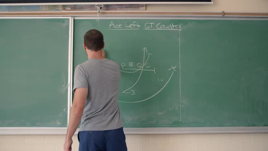A teacher is drawing a math problem on a chalkboard