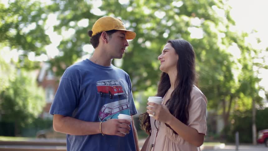 A boy and girl are holding hands and coffee and staring at each other