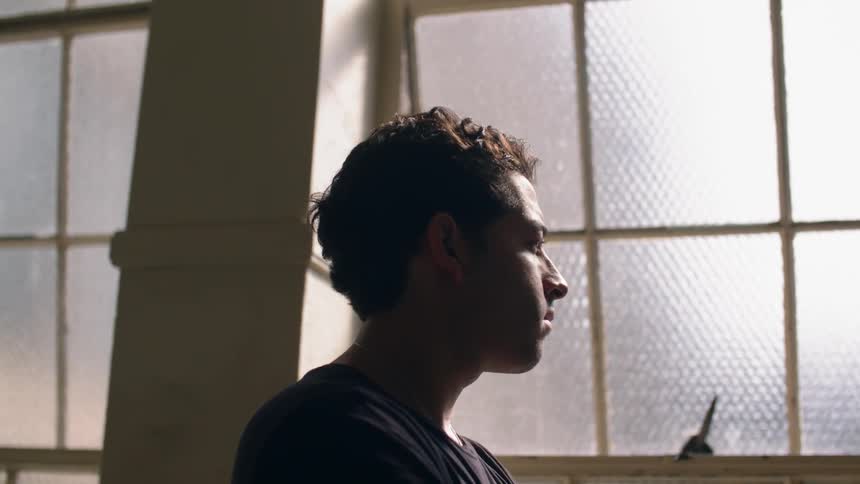 A man looks out the window in the dark room