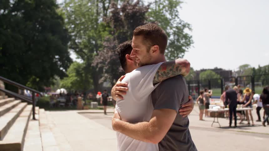 Two people are hugging at the steps outside at a park
