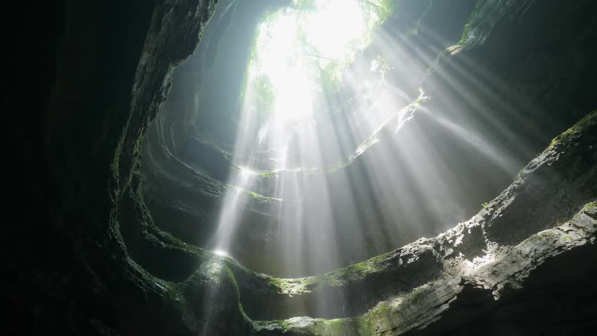 Looking up at the cave opening with the sun shining through