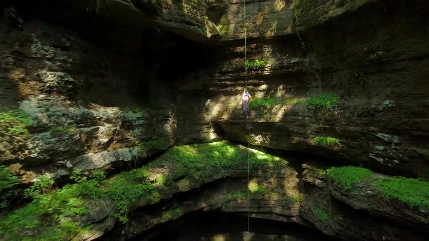 A man climbs up a rope in a canyon