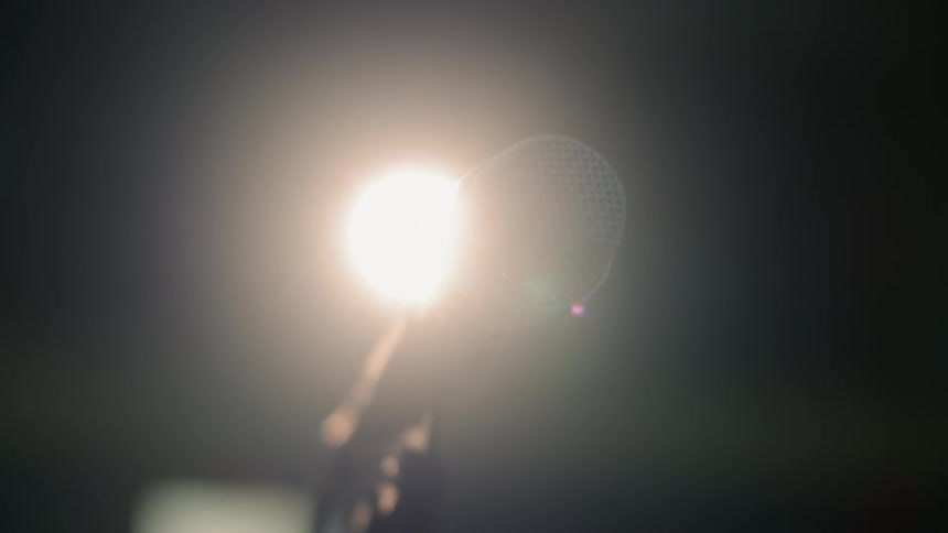 A microphone stand is illuminated by a bright light
