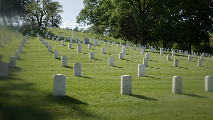 Rows of white tombstones in a cemetery on a sunny day