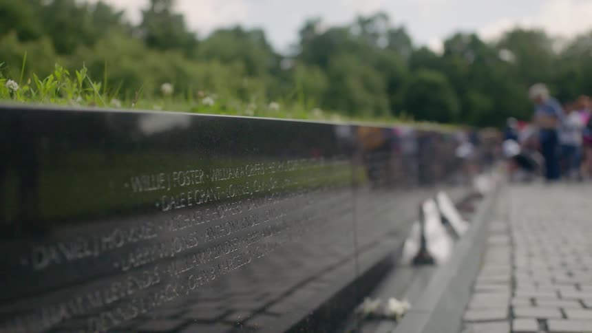 People walk and stand by a military monument