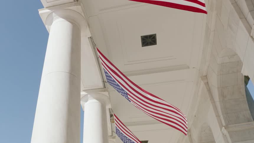 American flags breeze in the wind at a monument