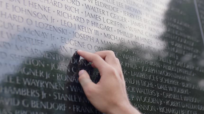 A person rubs their hands on a military personnel tribute