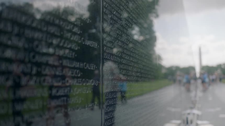 Tourists walk by a tribute to fallen military personnel