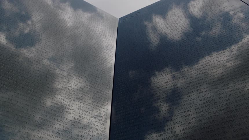 Rain clouds are reflecting in a monument etched with many names