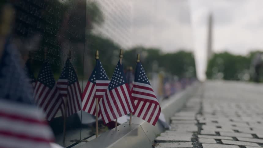 American flags sit next to a memorial wall