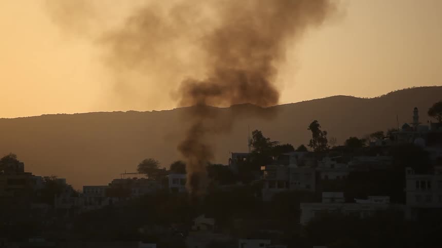 A fire burning from a village near a mountain