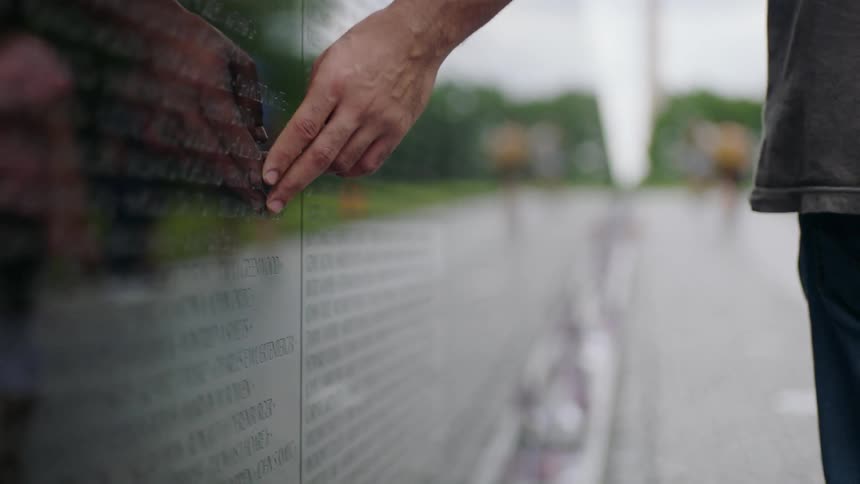 Man rubs his hand on a memorial wall
