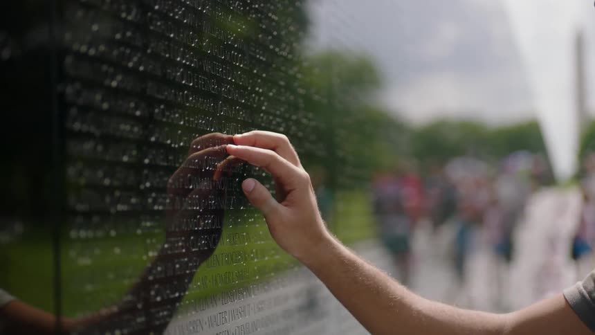 A man touches a memorial wall