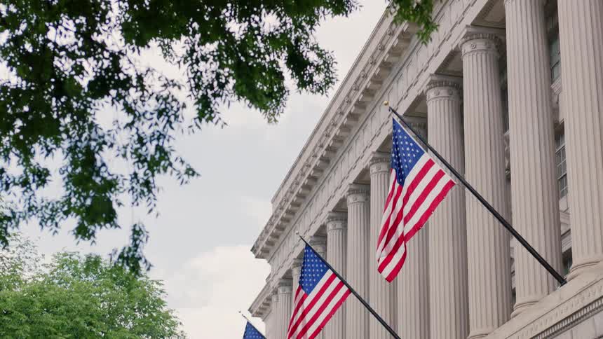 American flags hang outside of a monument building