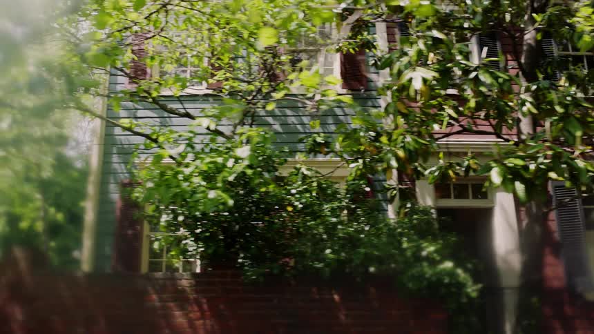 An old neighborhood is filmed from a passing car