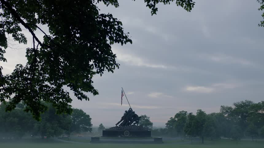 A war monument is shown in the distance at dusk